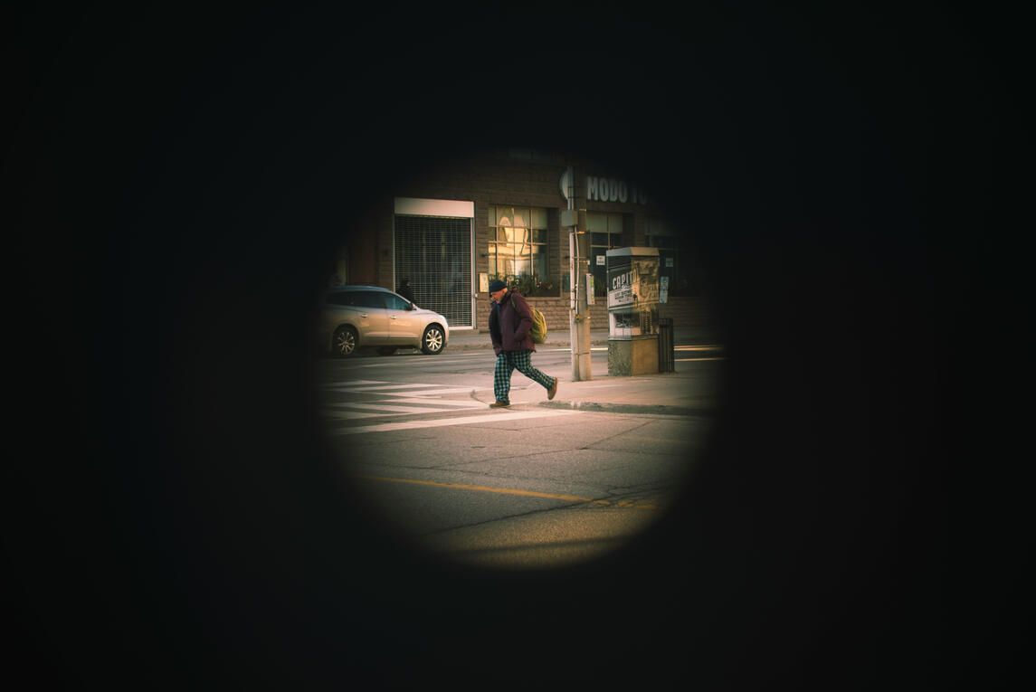 Shot of a walking man taken through a hole in a sign post