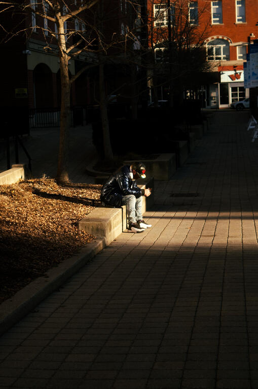 A lone man listening to music as a patch of light spills over him